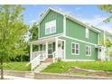 Attractive two-story home boasts green siding, white trim, covered front porch, and well-maintained lawn at 2427 N Rural St, Indianapolis, IN 46218