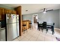 Open-concept dining area with bar, tiled floor, ceiling fan, stainless steel refrigerator, and a dining table at 2833 Desoto Way, Columbus, IN 47203