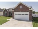 Brick home with a two-car garage, concrete driveway, and green grass yard in a suburban neighborhood at 5755 Victory Dr, Columbus, IN 47203