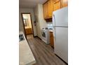 Galley kitchen featuring wood cabinetry, white appliances, and wood-look floors at 705 Orchard Ln, Greenwood, IN 46142