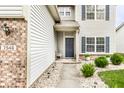 Close up of the front door with blue door, stone walkway, and tidy shrubbery at 7546 Kidwell Dr, Indianapolis, IN 46239