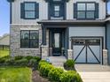 Home featuring a stone facade, a covered front porch, and landscaped flower beds at 8635 Verbena Rd, Zionsville, IN 46077