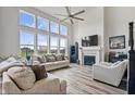 Spacious living room features tall windows, a ceiling fan, fireplace, and hardwood floors at 8635 Verbena Rd, Zionsville, IN 46077