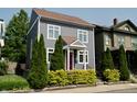 Charming two-story home featuring gray siding, complemented by lush green landscaping and a vibrant red front door at 1021 N Alabama St, Indianapolis, IN 46202