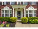 Inviting front entrance with decorative columns, manicured bushes, and colorful flowers at 10248 Noble Ct, Indianapolis, IN 46234