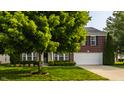 Beautiful brick home featuring a manicured lawn, mature trees, and an attached two-car garage at 10248 Noble Ct, Indianapolis, IN 46234