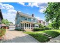 Inviting two-story home featuring a charming front porch, well-manicured lawn and a detached two car garage at 140 W Hampton Dr, Indianapolis, IN 46208