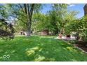 Spacious backyard with a manicured lawn, mature trees, and a patio area for outdoor entertaining at 1408 126Th St, Carmel, IN 46033