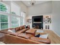 Open living space with tall windows, cozy leather sectional, and stylish fireplace at 14662 Woodstone Cir, Fishers, IN 46037