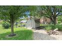 Backyard shed with a wooden access path, landscaping, and lush green grass at 5431 Nathan Pl, Indianapolis, IN 46237