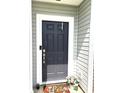 Close-up of the front door with a Hello mat and potted flowers, creating a welcoming entrance at 5702 Deer Valley Ct, Columbus, IN 47201