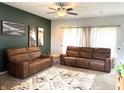 Cozy living room with leather sofas, a ceiling fan, and large windows with natural light at 5702 Deer Valley Ct, Columbus, IN 47201