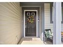 Close up of the main front door with a floral wreath and outdoor seating at 5966 Draycott Dr, Indianapolis, IN 46236