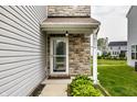 Close-up of the front door with stone accents and lush landscaping at 6114 Pebblebrooke Rd, Whitestown, IN 46075