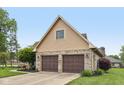 Side view of the two-car garage featuring brick accents and mature landscaping at 6983 White Oak Dr, Avon, IN 46123