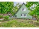 Unique green home with a distinct architectural design and luscious lawn framed by lush greenery at 715 Kessler Blvd E Dr, Indianapolis, IN 46220