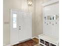 Bright foyer boasts a white door, coat rack and bench with basket storage and a decorative light fixture at 7430 Railway Ct, Indianapolis, IN 46256