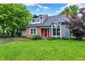 Charming front exterior featuring a brick facade and inviting red door, with mature trees and a lush lawn at 7430 Railway Ct, Indianapolis, IN 46256