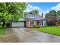 Charming front exterior featuring a brick facade and inviting red door, with mature trees and a lush lawn at 7430 Railway Ct, Indianapolis, IN 46256