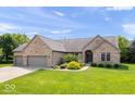 Charming brick ranch home boasts an attached three-car garage and a verdant front yard at 745 Ridge Gate Dr, Brownsburg, IN 46112