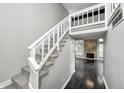 Bright staircase with a white railing, leading to a stone fireplace, and dark hardwood floors at 7507 Choate Ct, Indianapolis, IN 46254