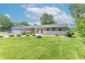 Charming single-story home with a well-manicured lawn, flower beds, and attached garage at 7850 S Mooresville Rd, Indianapolis, IN 46113