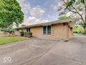 Side view of the brick home with a spacious driveway and lush greenery surrounding the property at 8071 Chiltern Dr, Indianapolis, IN 46268