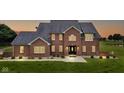 Elegant brick home with warm interior lights glowing, set against a twilight sky and lush green lawn at 8371 N 400 W, Fairland, IN 46126