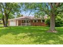 Charming brick ranch home featuring an attached garage, a manicured lawn, and mature shade trees at 9458 Dawn Dr, Brownsburg, IN 46112