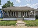 Charming single-story home featuring a cozy front porch with wood railings and a well-maintained lawn at 1033 Cottage Ave, Columbus, IN 47201
