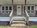 Inviting front porch with wood railings, steps, and white door, perfect for relaxing outdoors at 1033 Cottage Ave, Columbus, IN 47201