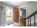 Bright foyer with tile flooring, coat rack, stairs with wood railing and view of the hardwood flooring in next room at 11461 N College Ave, Carmel, IN 46032