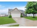 Charming home featuring a two-car garage, well-maintained lawn, and mature tree, enhancing curb appeal at 11521 Short Iron Ln, Indianapolis, IN 46235