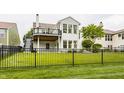 Beautiful backyard featuring an iron fence, lush green grass, a cozy deck, and mature trees at 13091 Duval Dr, Fishers, IN 46037