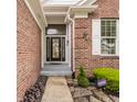 Close-up view of the home's entrance, featuring a decorative glass front door, brick siding, and stone walkway at 13091 Duval Dr, Fishers, IN 46037