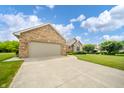 Classic brick home featuring a wide driveway, an attached garage, and a well-kept lawn with mature trees at 1324 N Stewart Rd, Anderson, IN 46012