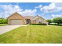 Attractive brick home with a two-car garage, surrounded by green lawns and well-maintained landscaping at 1324 N Stewart Rd, Anderson, IN 46012