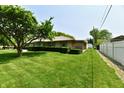 Side view of a well-maintained brick house with green lawn, mature tree, and fenced backyard at 1910 Ivy Dr, Anderson, IN 46011