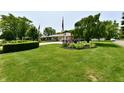 Well-maintained front yard with lush green lawn, mature trees, and colorful flowerbeds enhancing curb appeal at 1910 Ivy Dr, Anderson, IN 46011