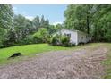 Side view of a well-maintained home with gravel drive surrounded by a green lawn and mature trees at 2640 S Silcox Rd, Paragon, IN 46166