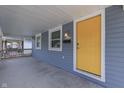 Inviting front porch featuring a bright yellow front door, freshly painted siding, and a modern wall sconce at 2945 N Denny St, Indianapolis, IN 46218