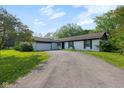 Inviting single-story house with a white brick facade, black trim, a paved driveway, and lush green lawn under a blue sky at 3141 Citadel Ct, Indianapolis, IN 46268
