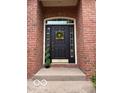 Charming front door entrance with brick surround, accent topiary, and a wreath on the door at 458 Burlington Ln, Carmel, IN 46032