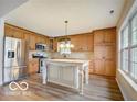 Modern kitchen with wood cabinets, stainless steel appliances, a central island, and bright windows at 5651 Pine Knoll Blvd, Noblesville, IN 46062