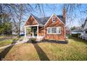 Lovely brick home with manicured lawn, covered porch, and mature trees in a serene setting at 6640 E Washington St, Indianapolis, IN 46219