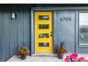 Close up of the eye-catching yellow front door with black hardware, potted red flowers and the house number at 6704 Hoover Rd, Indianapolis, IN 46260