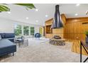 Bright living room featuring a statement cone fireplace, built-in wood shelving and seating area with blue sofa and accent chair at 6704 Hoover Rd, Indianapolis, IN 46260