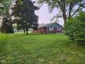 A brick home with white trim and a large lawn surrounded by mature trees under a cloudy sky at 7870 E County Road 150 S, Avon, IN 46123