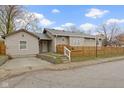 Home featuring beige siding, concrete driveway, and wood fence creating a welcoming and well-defined space at 802 N Tuxedo St, Indianapolis, IN 46201