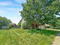 Spacious front yard featuring lush green grass and a mature shade tree partially obscuring the charming two-story home at 812 Timber Creek Dr, Indianapolis, IN 46239